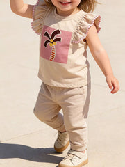 Baby girls' tan cotton tee with playful palm tree graphic and pink pom-pom ruffle sleeves.