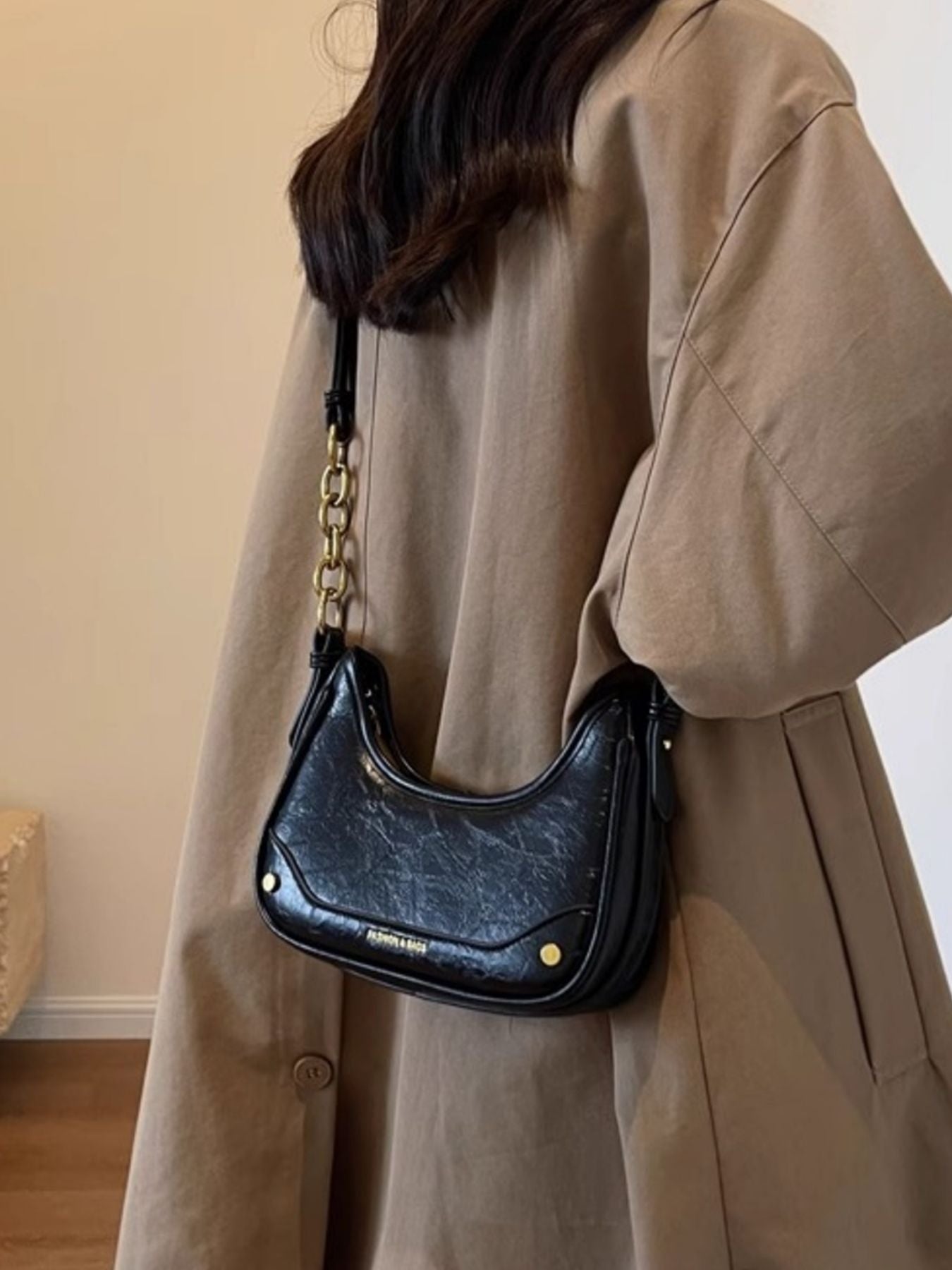 Black crescent shoulder bag with chunky chain strap and gold hardware.