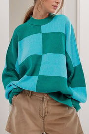 Checkerboard knit oversized sweater in turquoise and green with a mock neck and long sleeves.