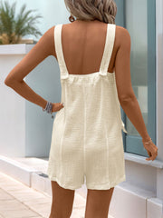 Textured button-down summer romper in cream with button straps and a tie detail.