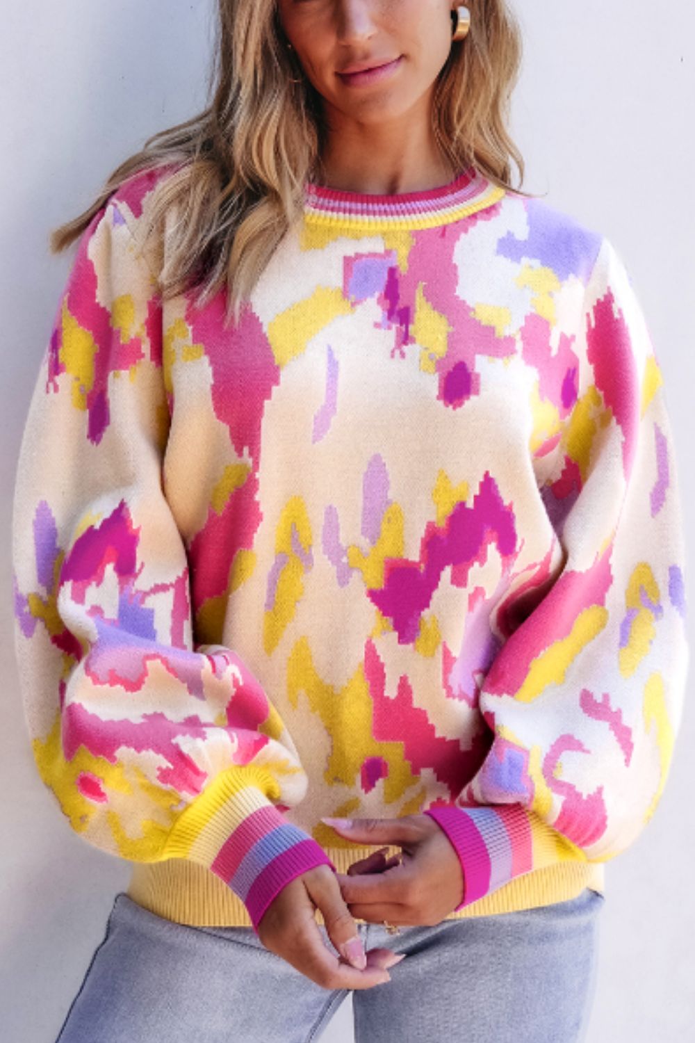 Abstract brushstroke knit sweater with puff sleeves and striped cuffs in floral colors.