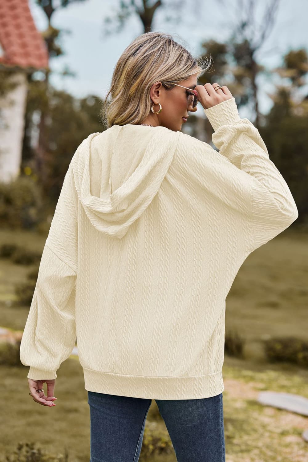 Ivory textured cable knit hoodie with a zip-up front and hood.