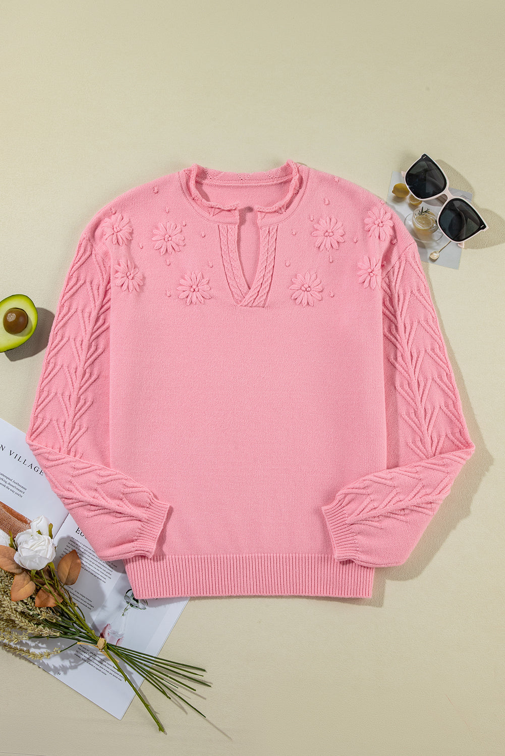Pink knit sweater with embroidered floral details and notch neck.