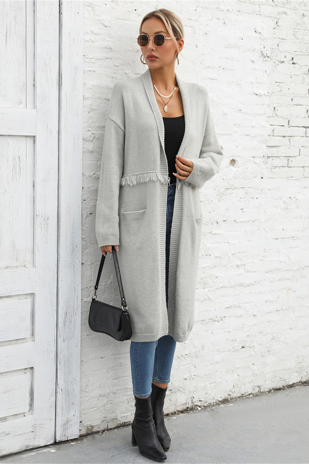 Light gray longline knit cardigan with fringe trim and pockets.