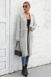 Light gray longline knit cardigan with fringe trim and pockets.
