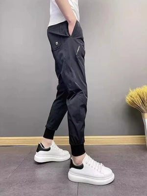 Black cotton sweatpants with ankle cuffs and zippered pocket detail.