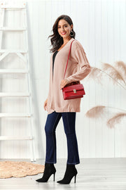 Apricot cable knit open front cardigan with textured sleeves, styled with dark wash jeans and black heeled boots.