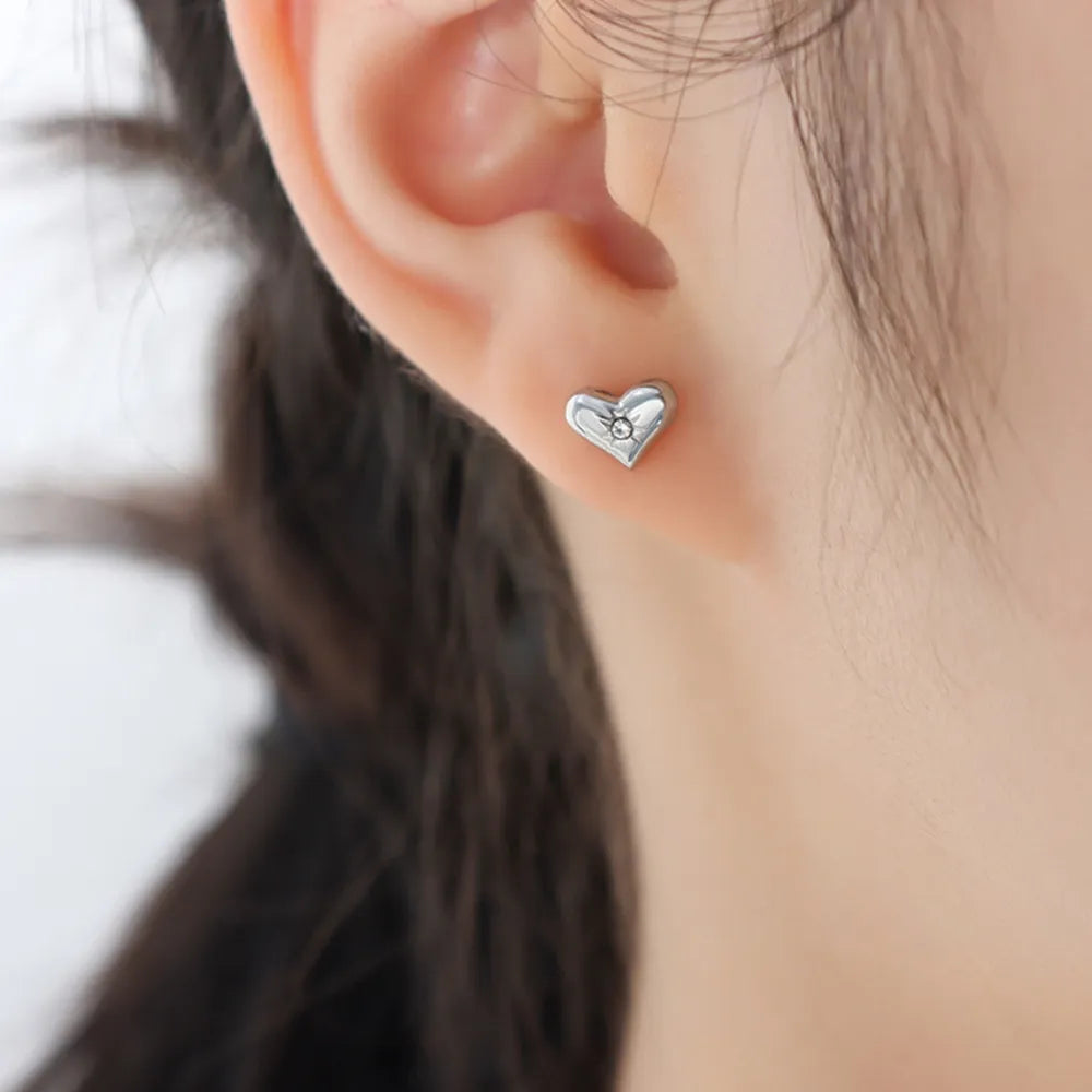Silver heart stud earrings with a small diamond accent, perfect for daily wear.