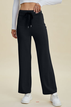 Black wide leg lounge pants with drawstring waist and white sneakers