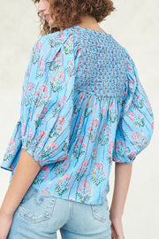 Sky blue floral print smocked yoke blouse with puff sleeves and striped pattern.