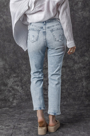 Light wash distressed denim jeans with a slim leg cut, shown from the back.