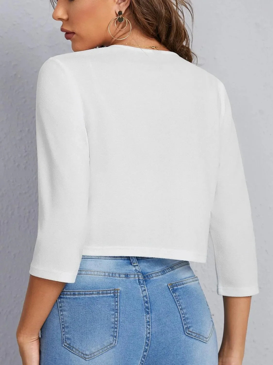 White cropped open-front blazer with elbow sleeves and a textured finish.