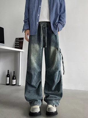 Relaxed fit blue denim cargo jeans with drawstring waist and utility pocket detail.