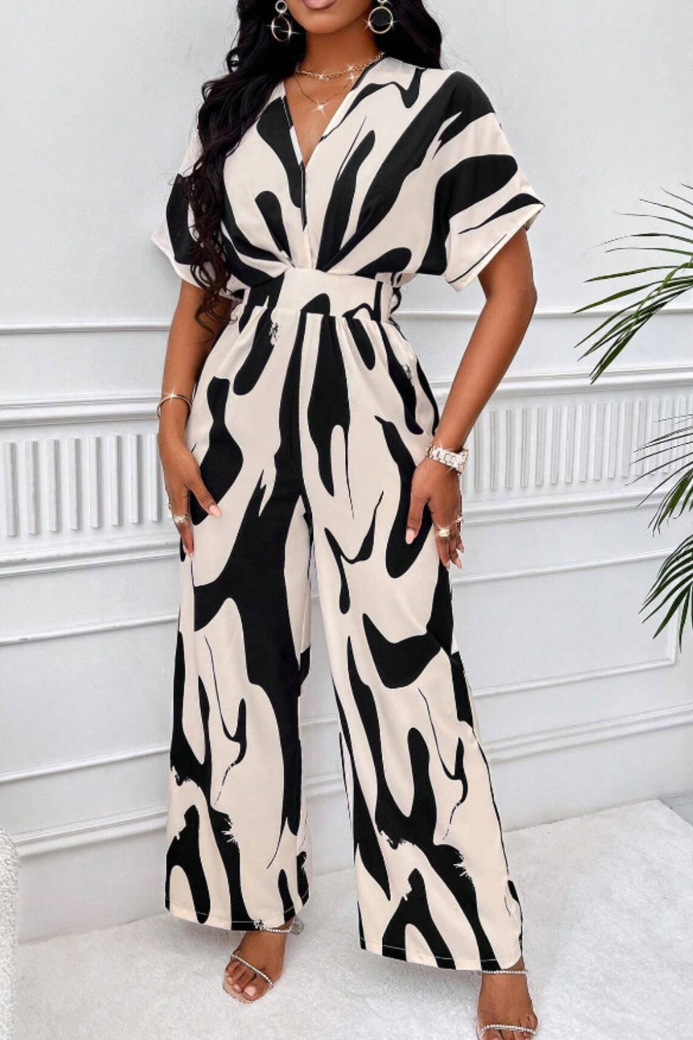 Abstract brushstroke wide-leg jumpsuit in black and taupe with a V-neck and short sleeves.