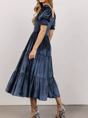 Dusty blue velvet midi dress with smocked bodice and ruffled puff sleeves.