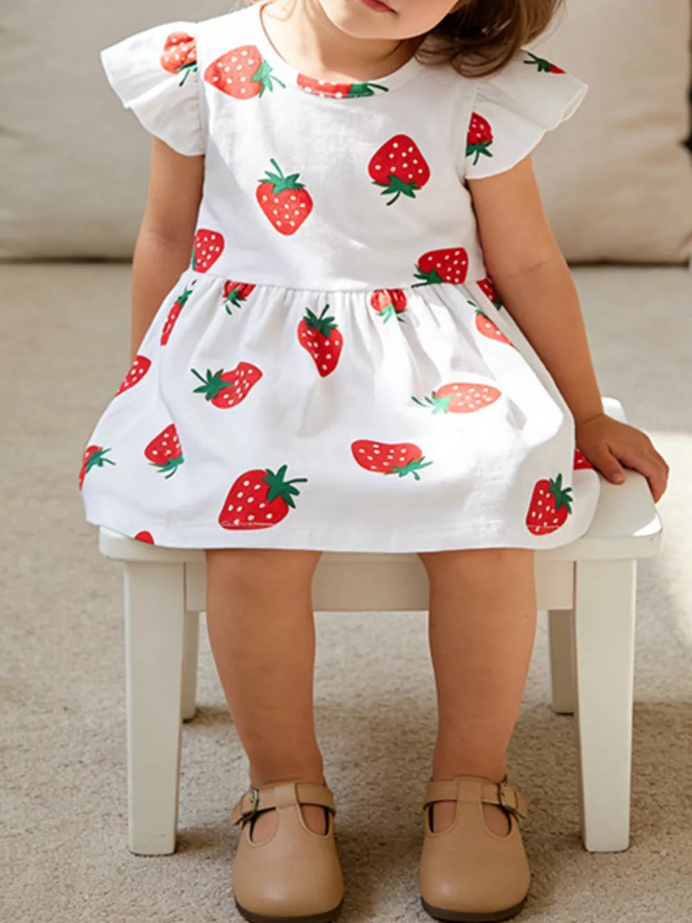 Baby dress with strawberry print, ruffle sleeves, and gathered skirt.