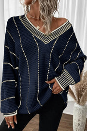 Dark navy knit oversized V-neck sweater with white and gold stripe details and waffle texture.