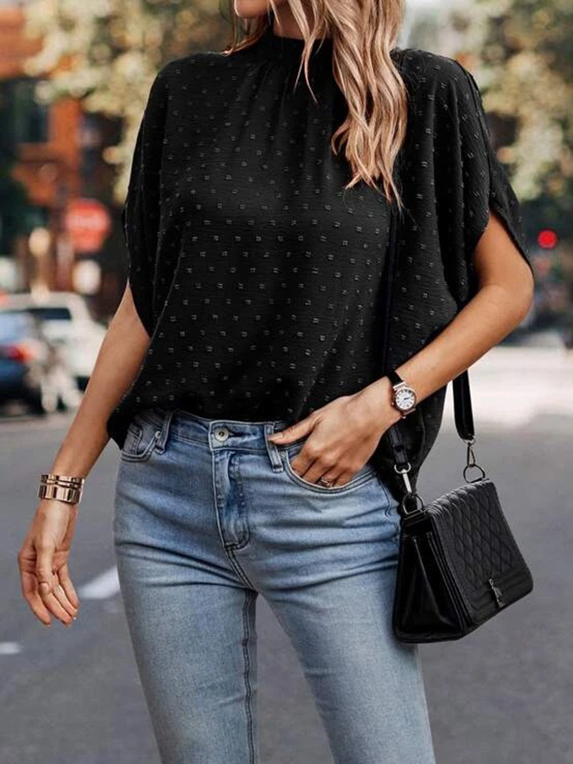 Black textured dot back-tie blouse with short sleeves and mock neck.