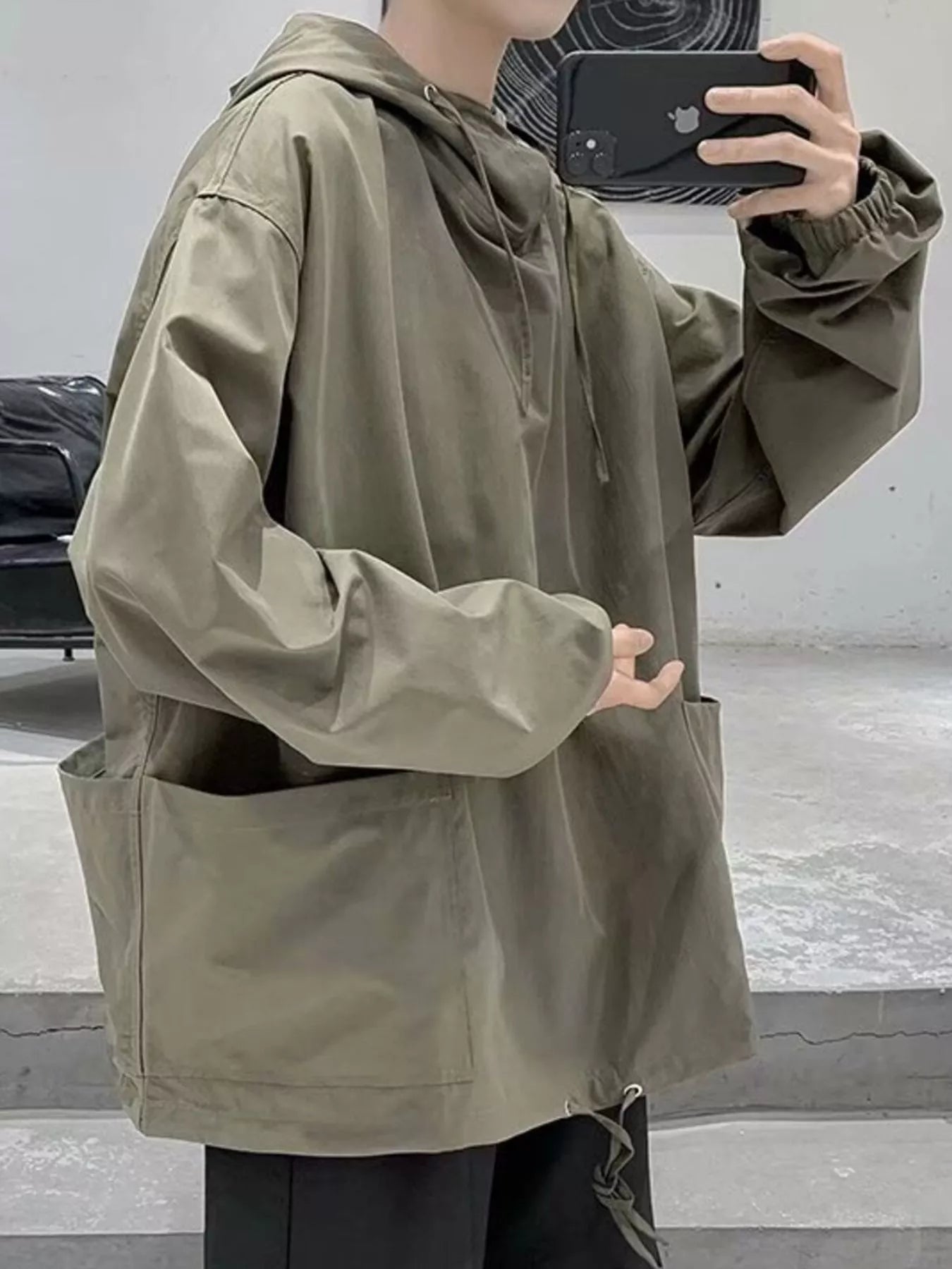 Oversized green drawstring hoodie with large front pockets and cinched cuffs.