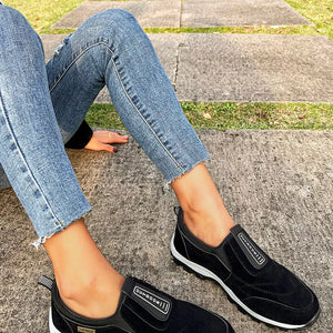 Black suede-like round toe slip-on sneakers with elastic side panels and white soles.