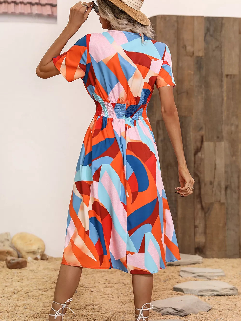 Vibrant abstract pattern midi dress with smocked waist and short sleeves.