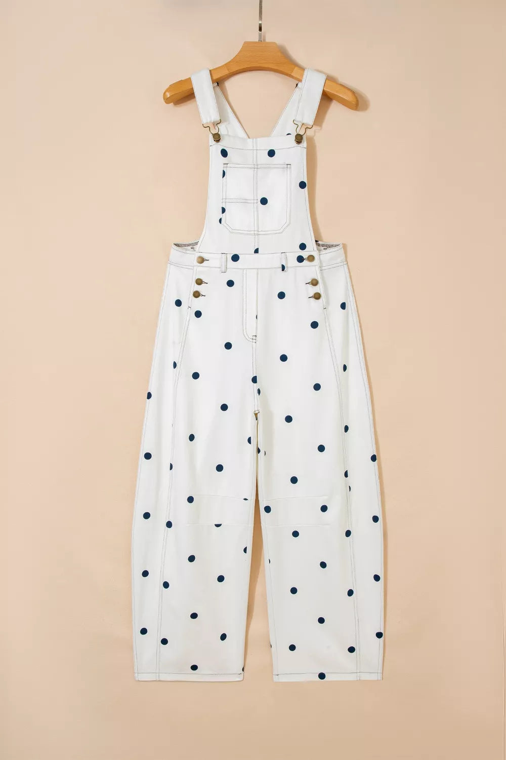 White denim overalls with navy polka dots, buttoned sides, and adjustable straps.