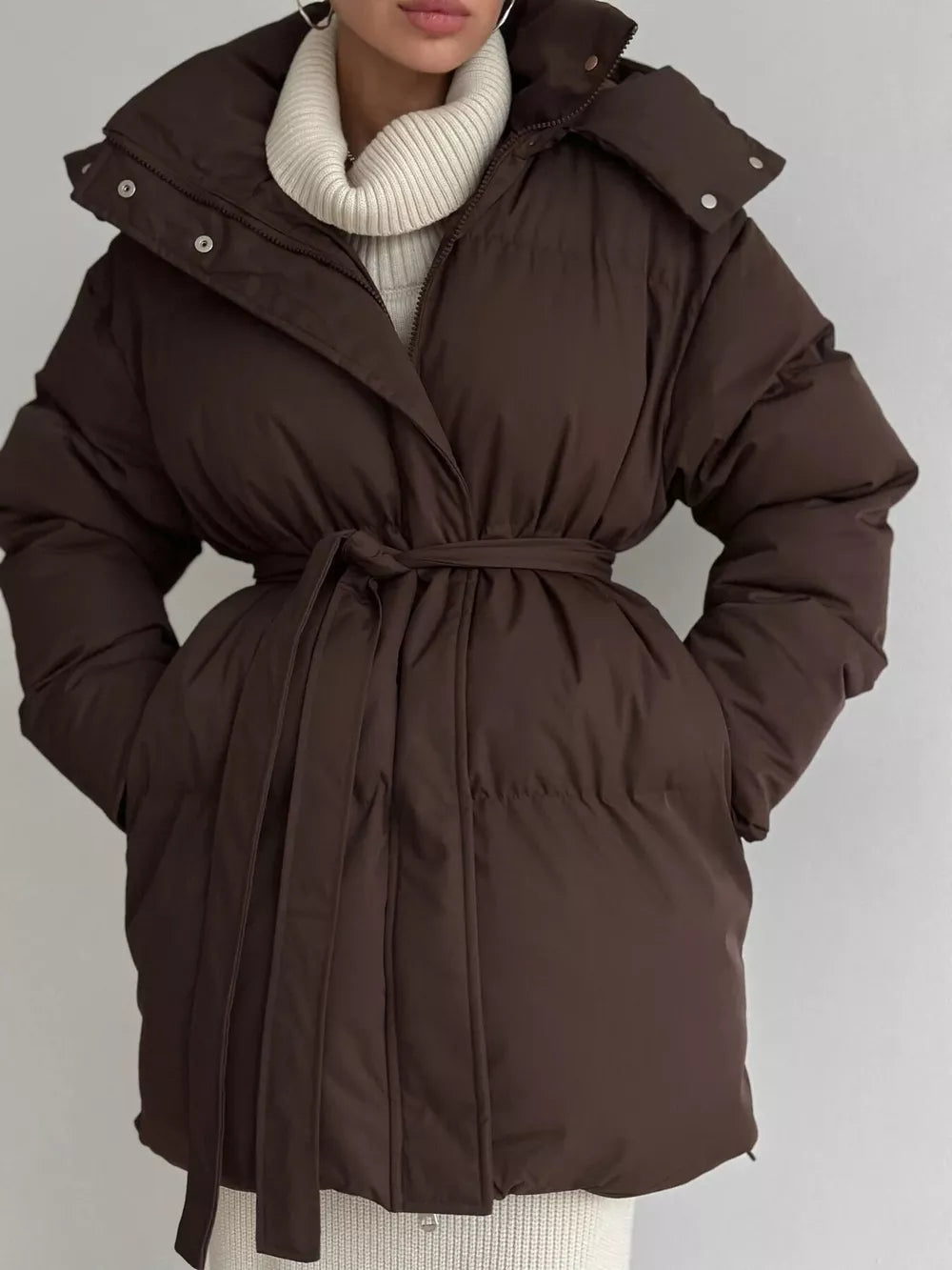 Dark brown belted puffer trench coat with hood, buttoned closure, and tie waist.