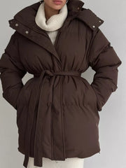 Dark brown belted puffer trench coat with hood, buttoned closure, and tie waist.