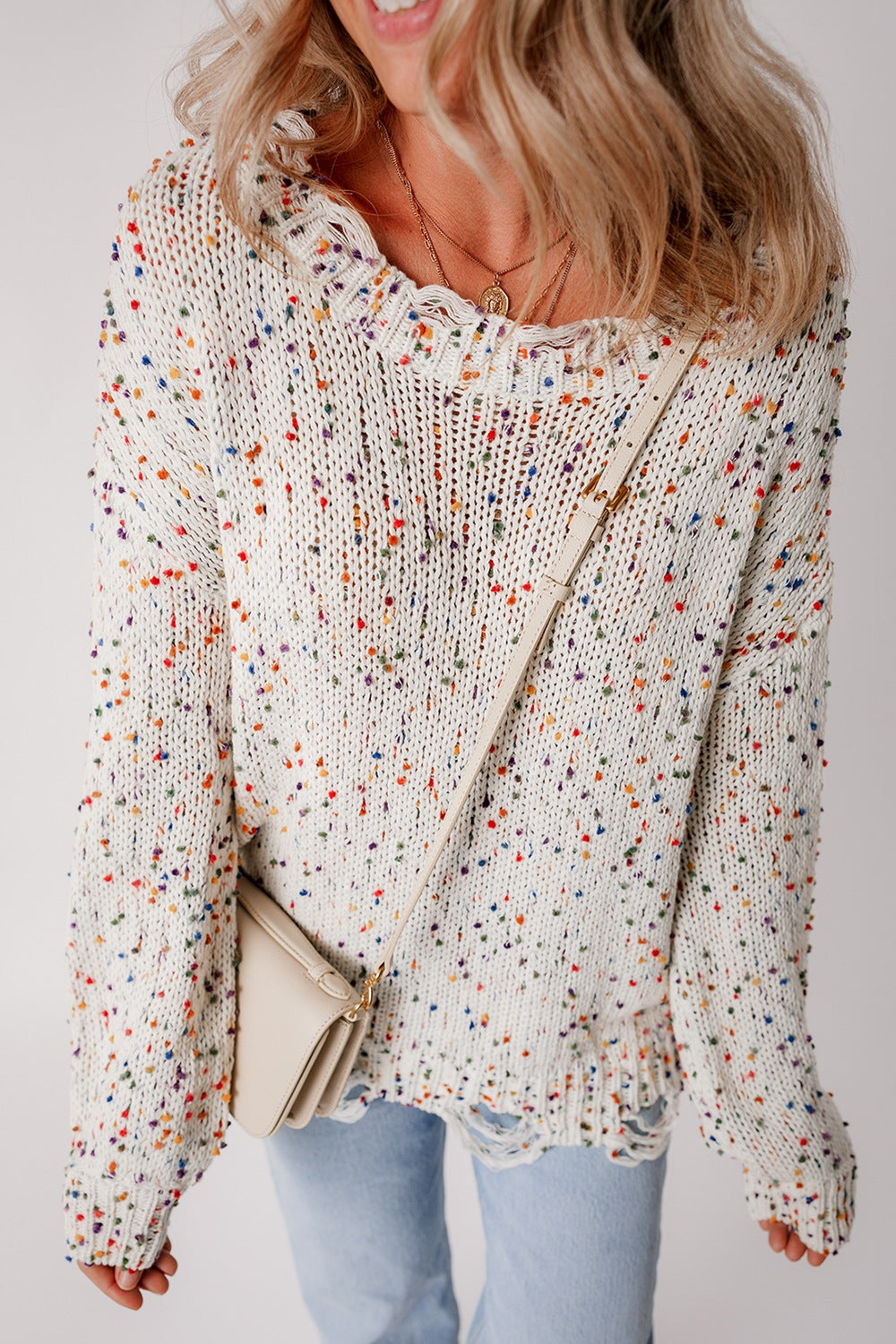 White confetti knit sweater with distressed hem and colorful flecks.
