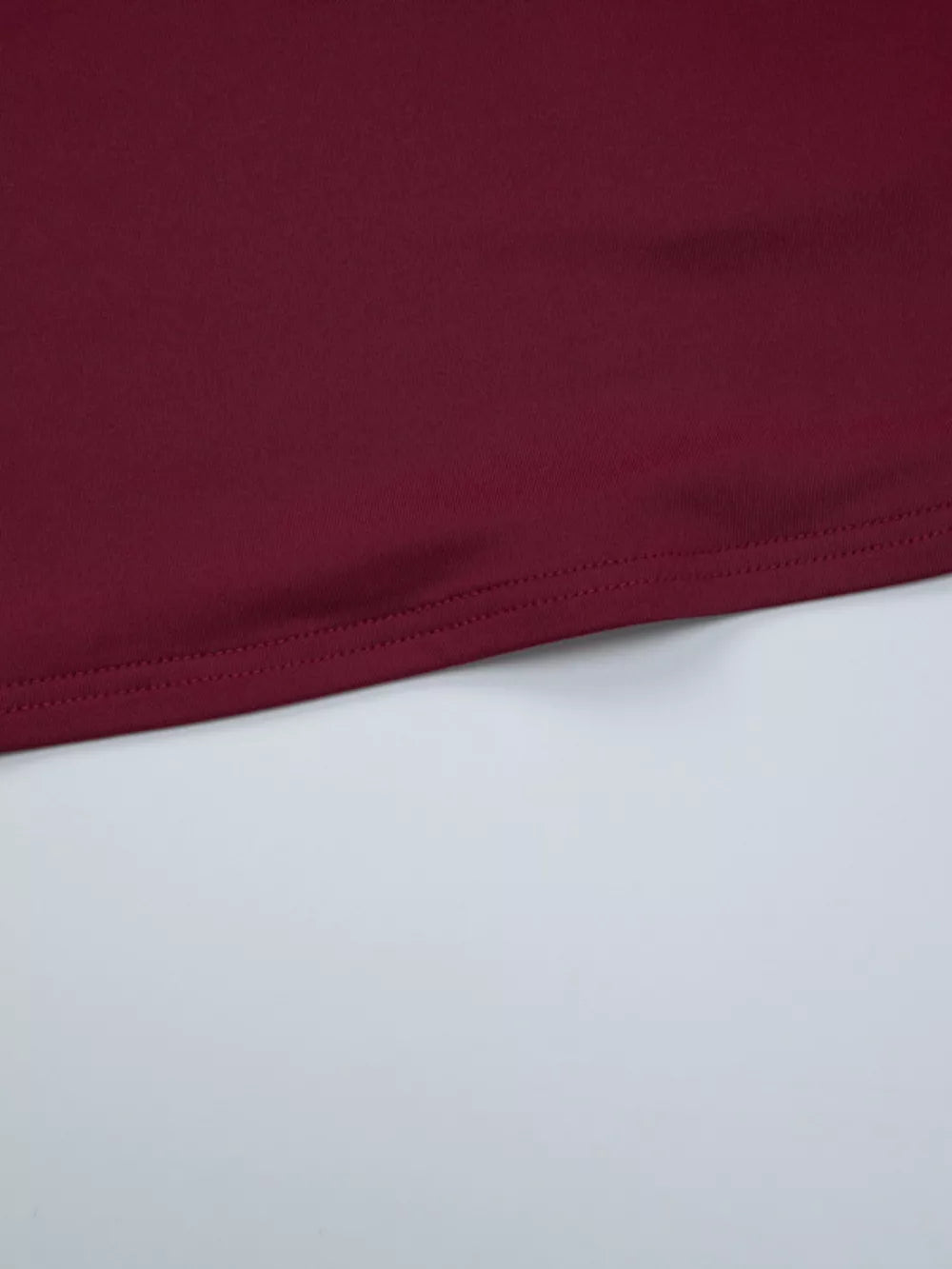 Wine red t-shirt with a cropped hem and visible stitching detail.