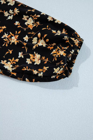 Black long-sleeve blouse with delicate floral print and smocked cuff detail.