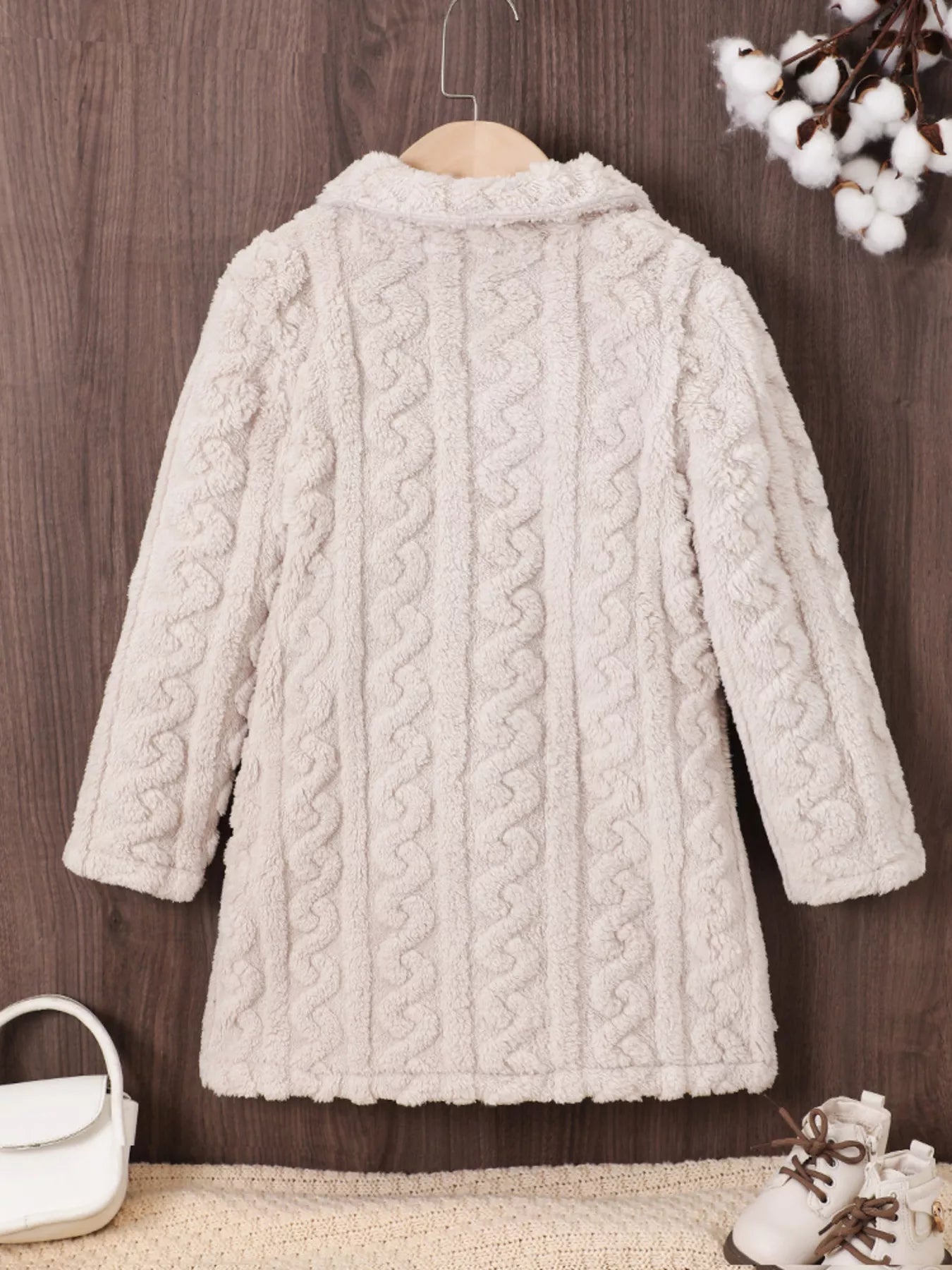 Baby pea coat in eggshell with cable knit texture and plush fabric.