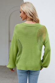 Green knit sweater with cutout details on the back and sleeves.