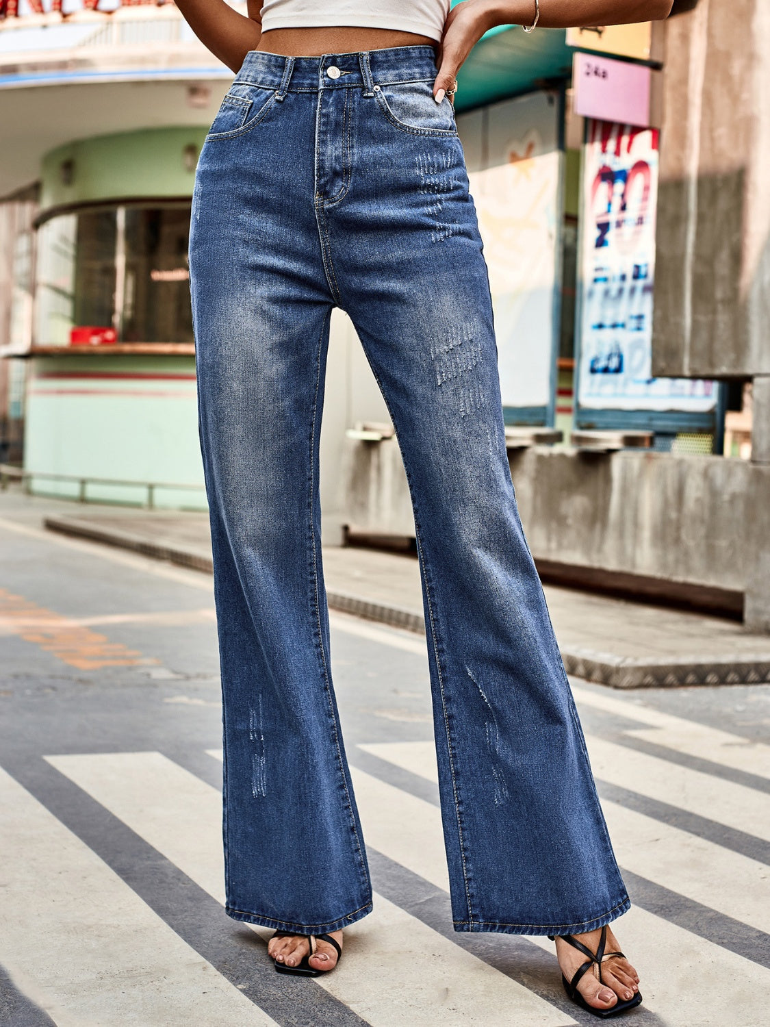 Dark blue denim flare jeans with distressed details and a buttoned fly.