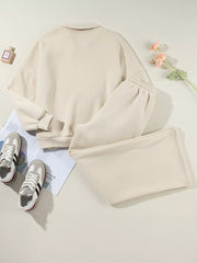 Beige cotton zip-up jacket and drawstring pants set with cuffed sleeves and elastic waistband.