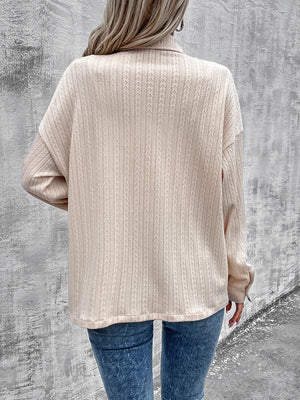 Beige textured overshirt with relaxed fit and buttoned collar, styled casually.