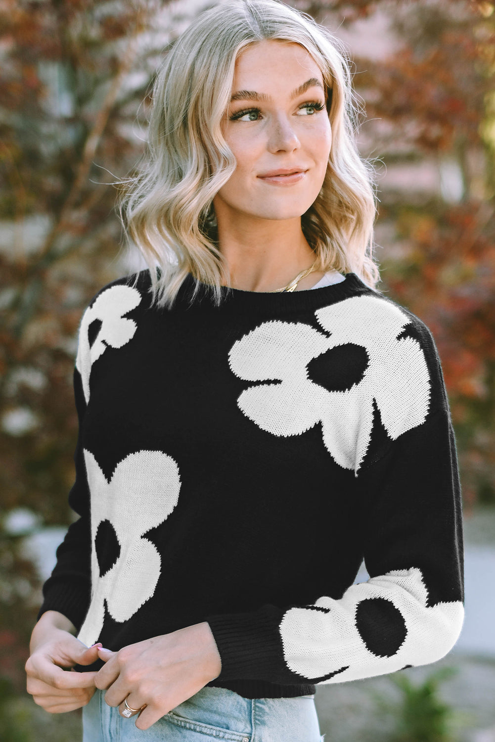 Black acrylic crewneck sweater with large white floral intarsia pattern.