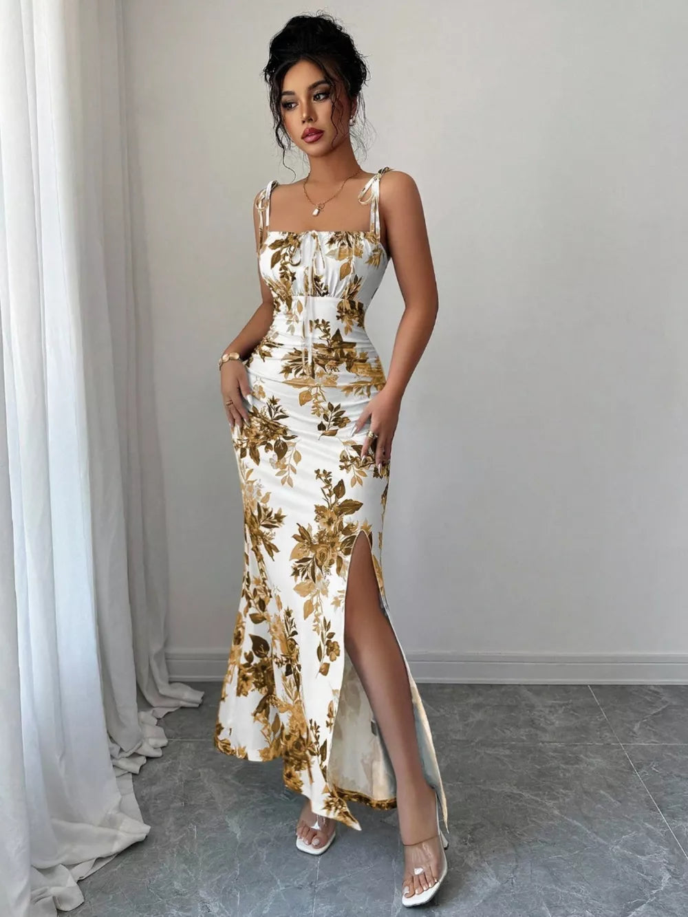 Floral print maxi dress with tie straps, sweetheart neckline, and high slit in white with gold floral pattern.