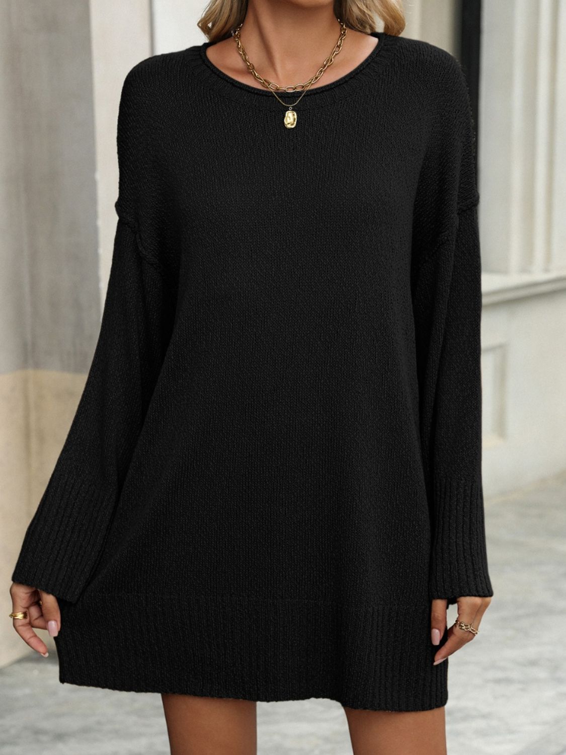 Black oversized ribbed knit tunic sweater with crew neck and long sleeves.