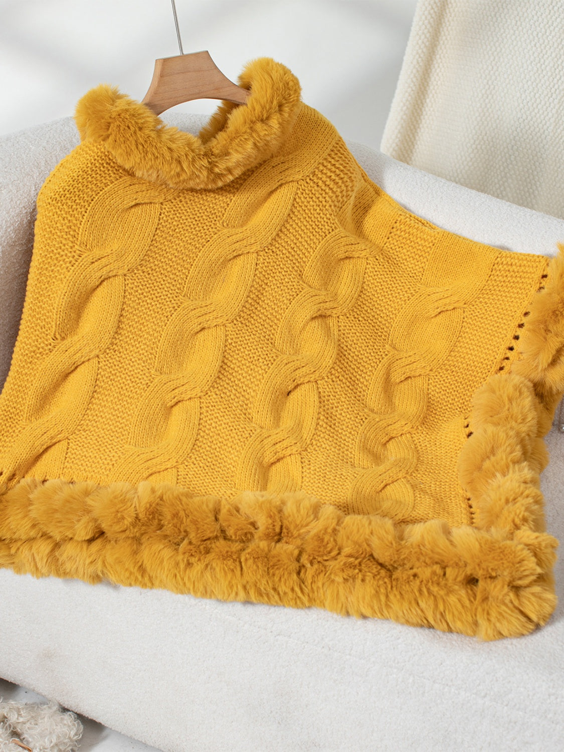 Gold cable knit poncho with faux fur trim and collar detail.