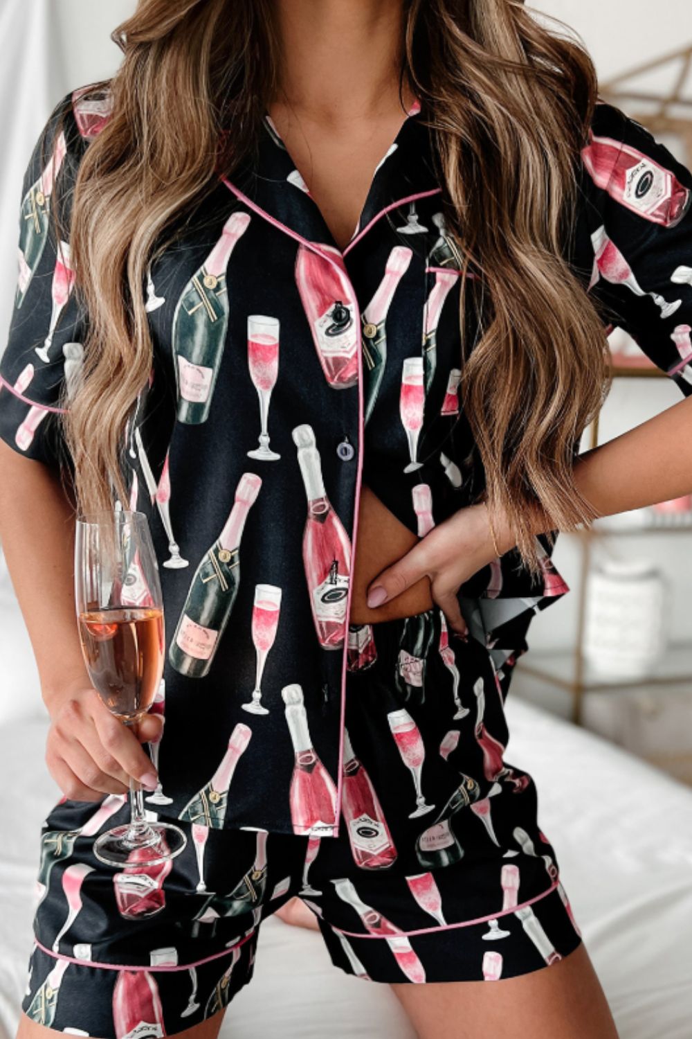 Black silk pajama set with champagne print, pink piping, and button-up top.