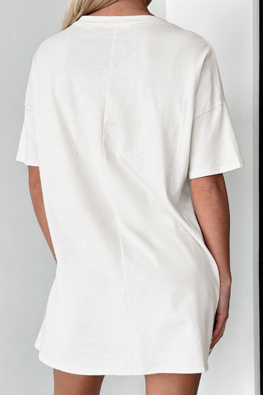 White oversized tee dress with short sleeves and a relaxed fit.