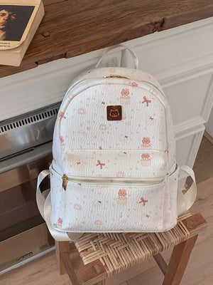 Charming mini backpack in ivory with playful cat and bow motifs, textured finish.