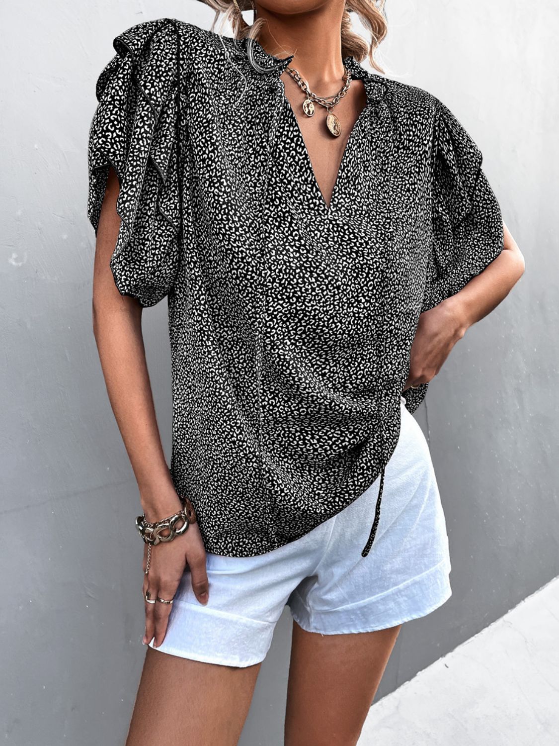 Black ditsy print blouse with ruffle sleeves and V-neck, cinched waist detail.
