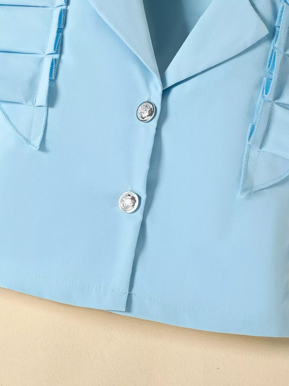 Blue collared toddler outfit with decorative buttons and ruffled trim.