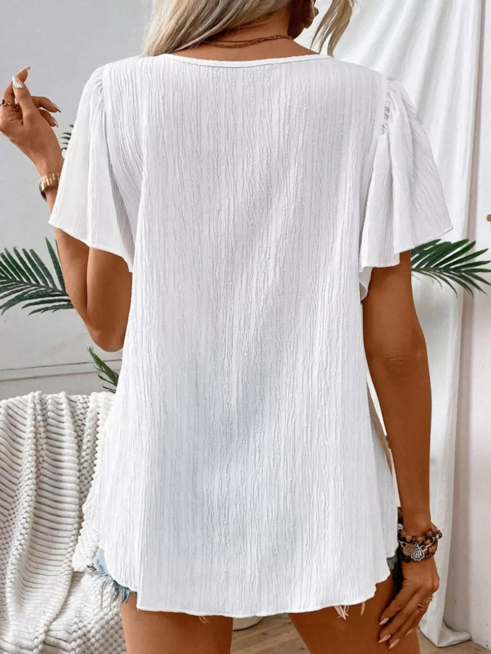 White embroidered square neck flutter blouse with textured fabric.