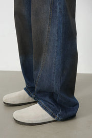 Faded panel wide-leg denim trousers in medium wash with visible seams.