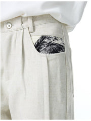 Men's ivory wide-leg trousers with a black palm leaf pocket detail.