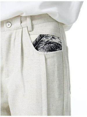 Men's ivory wide-leg trousers with a black palm leaf pocket detail.