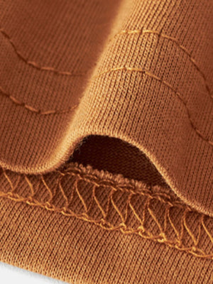 Burnt orange cotton t-shirt detail showing crew neck stitching and fabric texture.